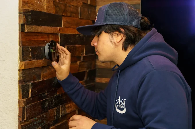 Professional thermostat installation on wall by A-OK Services technician San Antonio